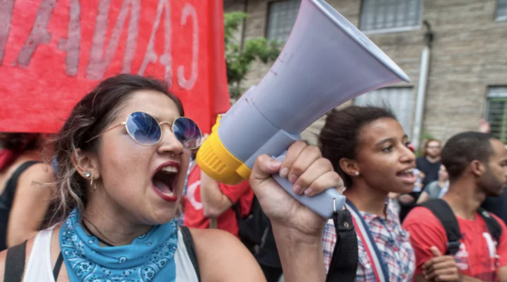 University age students protesting in a group with a megaphone